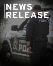 Image of the back of a police officer standing next to a marked police car